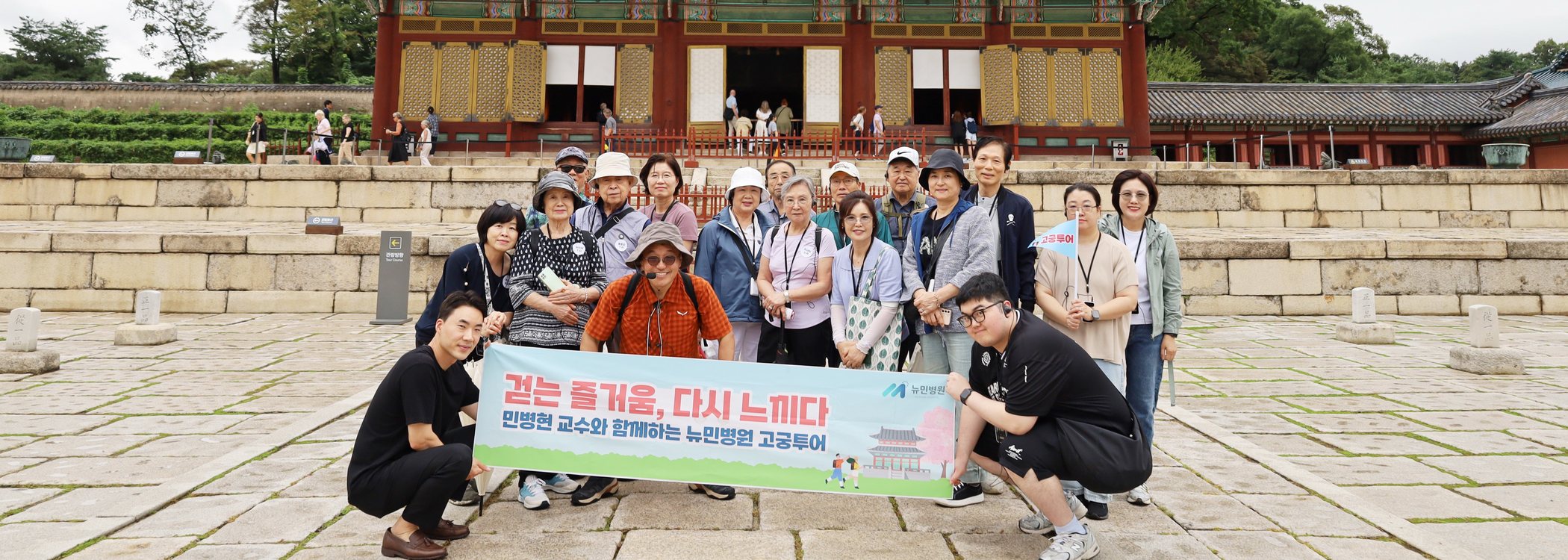 고궁 앞에서 '걷는 즐거움, 다시 느끼다' 현수막을 들고 함께 기념사진을 찍은 환우들과 뉴민병원 의료진